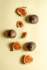 Top view fresh exotic cutted on half fig on yellow background. Food photo background. Creative scheme of the whole and sliced figs. Flat lay. View from above. Tasty summer fruit