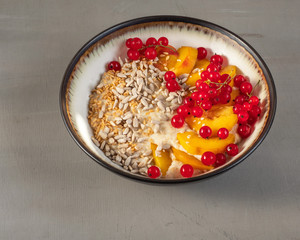Oatmeal porridge with fruits, berries and cereals, healthy and light Breakfast in a deep ceramic plate, close-up