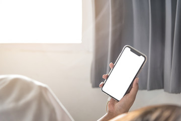 Asian Woman's hands using smartphone with blank screen in bedroom at morning.