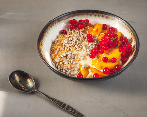 Oatmeal porridge with fruits, berries and cereals, healthy and light Breakfast in a deep ceramic plate and spoon,