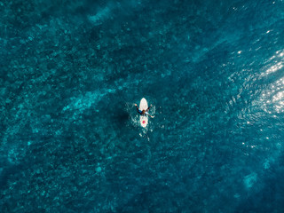 Aerial view of surfer in blue clear ocean. Top view