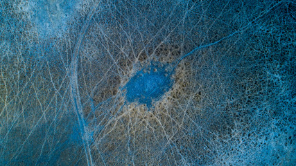 Aerial view of multiple animal tracks near a dirt road that converge at a dried-up waterhole near the Okavango Delta in Botswana in the dry season, producing abstract organic patterns