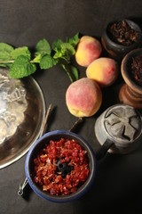 bowl with tobacco for hookah. fruits on a black background. smoking hookah