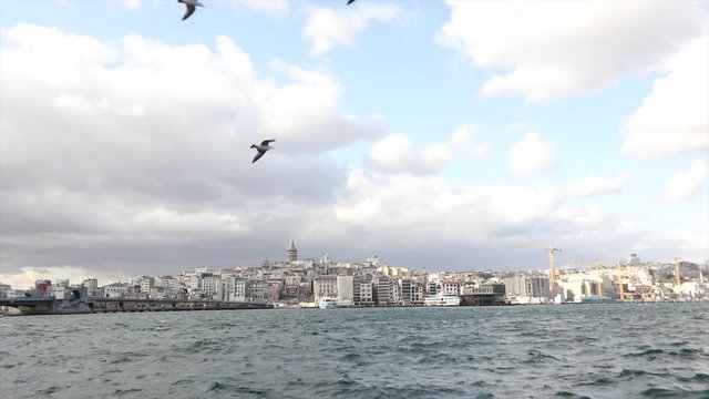 Galata Tower, in the foreground pleasure boats with tourists and seagulls. Pleasure boats on the background of the Galata Tower, windy weather