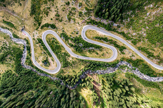 Winding road in the mountains. Forest and river nearby. Transfagarasan road in Trasnylvania, Romania, Europe.