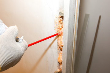 Man is installing the door with a spray foam. Repair works. Maintenance in the apartment.
