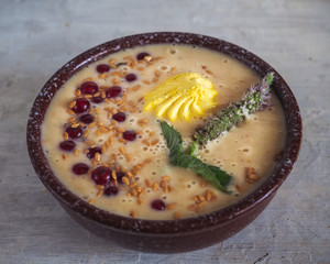 Fruit smoothie with yogurt and fresh fruits and berries and yellow marshmallows, a sprig of flowering mint in a deep dish,