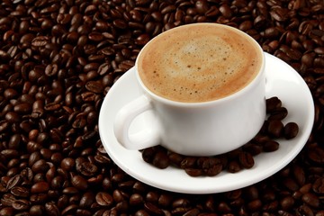 Cup of coffee surrounded by coffee beans
