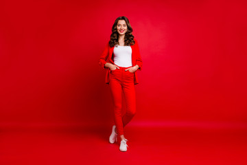 Full size photo of stunning lady with her hands put in pockets isolated over red background