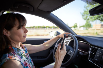 Fototapeta na wymiar woman driving her car while using the mobile