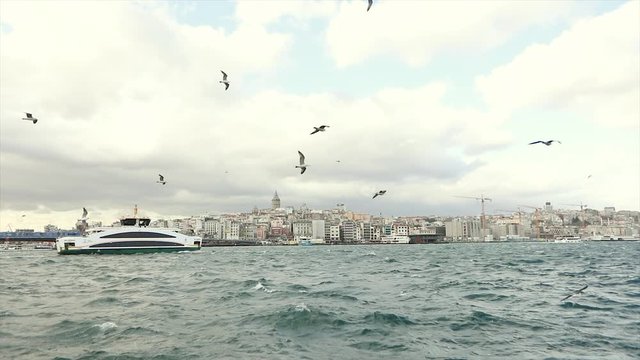 The ferry floats on the Bosphorus. A large modern yacht sails along the Bosphorus, in the background is the Galata Tower