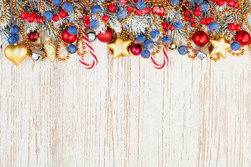 Christmas composition border flat lay top view. Red holly berries, blue berries, golden stars,...