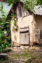 Old cob goat house with wooden door in countryside garden
