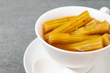 Vegetable of drumstick tree in spicy curry with coconut milk, in white bowl on concrete table.