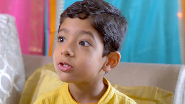 A cute little boy enjoys a piece of chocolate on raksha bandhan. 