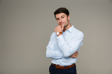 Image of confident serious man wearing wristwatch looking at camera and touching his chin