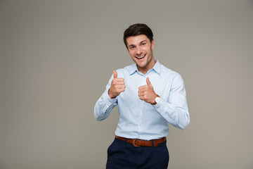 Image of cheerful brunette man wearing formal clothes smiling at camera while showing thumbs up