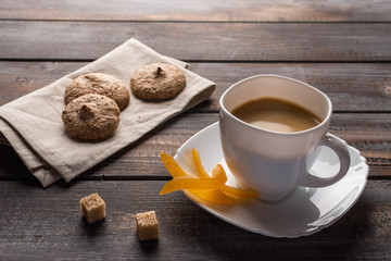 Cup of black coffee with candied oranges and lumps of sugar. Cookies on linen napkin