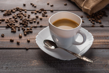 Cup of coffee with a spoon on a linen napkin. Coffee beans and bag