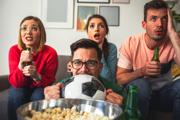 Group of cheerful friends watching soccer match at home