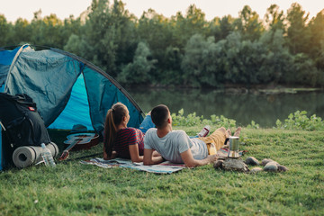 young couple enjoying camping outdoor by the river