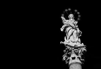 Statue of Virgin Mary of the Stars crushing dragon and crescent at the top of an ancient column in the historic center of Lucca, erected in 1687 (Black and White with copy space)