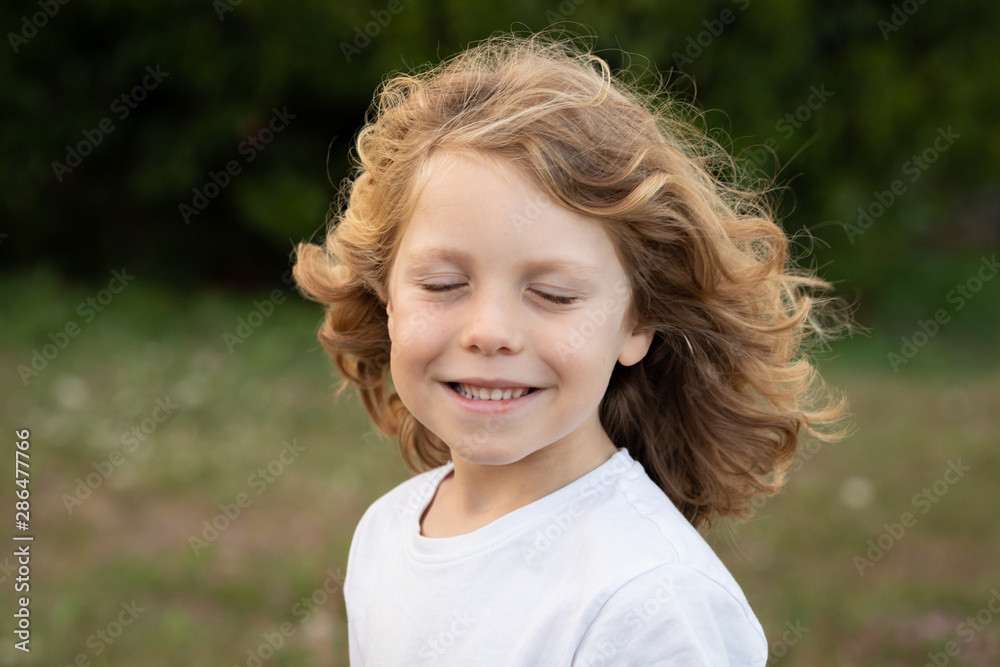 Wall mural Blond child laughing while imagines something in a park