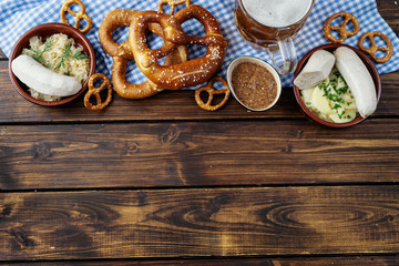Beer mug, pretzels and sausages on wooden table. Top view