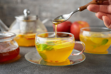 Pouring a honey into glass cup of fruit tea
