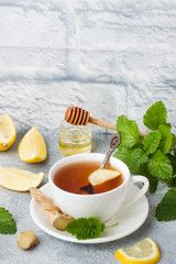 White Cup with natural herbal tea ginger lemon mint and honey. Gray background Copy space.