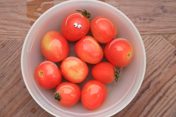 Red tomatoes in water, one with funny doll 's eyes, fresh fruits top view background.