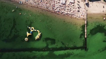 Aerial timelapse top view of a beach life during sunny summer day. A lot of people swimming in water