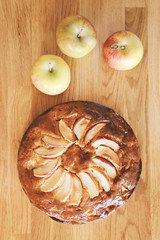 Homemade apple cake and fresh apples top view on wooden table, , toned image.