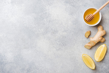 Lemon honey and ginger root on grey background with copy space. Ingredients for a tonic vitamin...