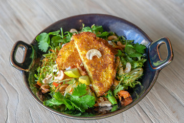 Organic veggie salad from broccoli, cashew , mild chilli and lime. Zesty and vibrant with galangal and kaffir lime. Topped with corn fritters and a rich paprika salsa on island Bali, Indonesia