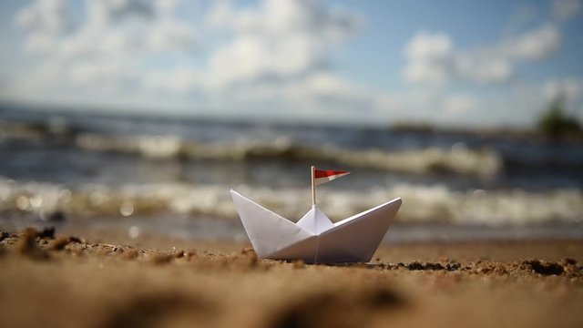 kleines Papierschiff am Strand in der Sonne