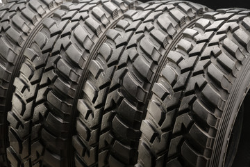 four off-road tires on black background. close up.