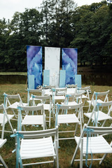 Beautiful outgoing wedding set up. Romantic wedding ceremony , wedding outdoor. Wedding decor. White wooden chairs on a green lawn. White armchairs for guests for the ceremony. 