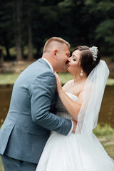 Sensual portrait of a young couple. Atractive wedding couple in love at the nature. Amazing wedding couple. Pretty bride and stylish groom. Beautiful wedding couple kissing