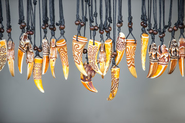 Magic amulets from teeth of animals hang on laces on the stand at the fair.