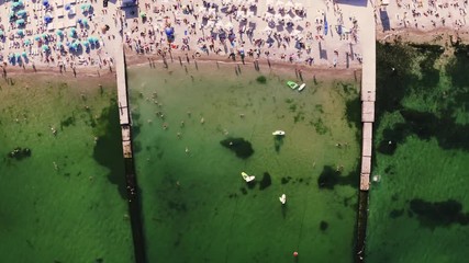 Aerial timelapse top view of a beach life during sunny summer day. A lot of people swimming in water