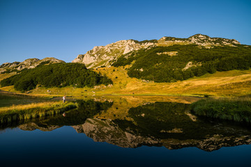 Fototapeta na wymiar Photographer taking photo on mountain lake in summer. 
