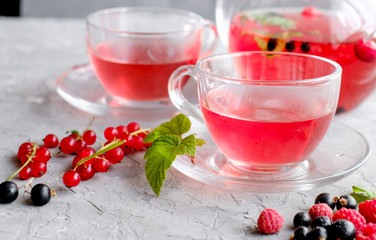 Fruits red tea with a berries in glass cup on gray cement background