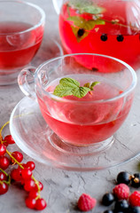 Fruits red tea with a berries in glass cup on gray cement background