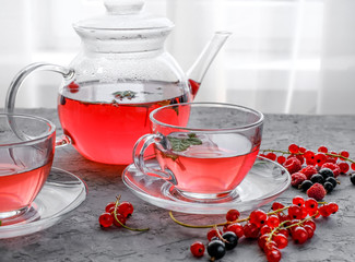 Fruits red tea with a berries in glass cup on gray cement background