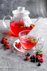Fruits red tea with a berries in glass cup on gray cement background