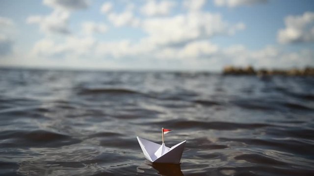 Papierschiff mit kleiner Flagge in den Wellen