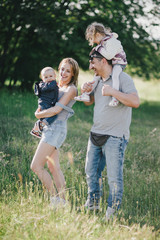 Happy family posing in a green park on sunny day.