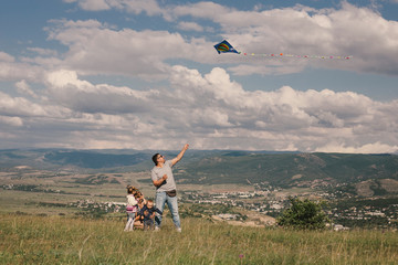 Happy family flying a colorful kite on green meadow.