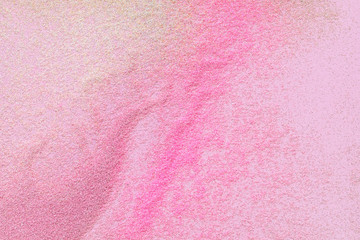 Many multi-colored spangles are scattered on a pink background.  View from above.  Place for text.